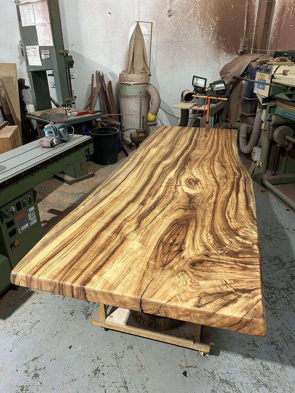 Long golden live-edge slab table in workshop