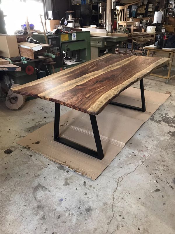 Dark live-edge table, trapezoid legs, workshop floor
