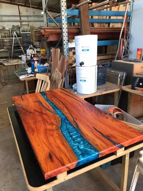 Orange marri table with a blue resin river, seen from the side