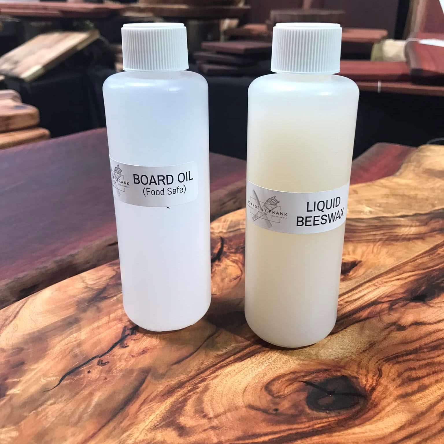 Bottles of food-safe board oil and liquid beeswax standing on a figured timber slab