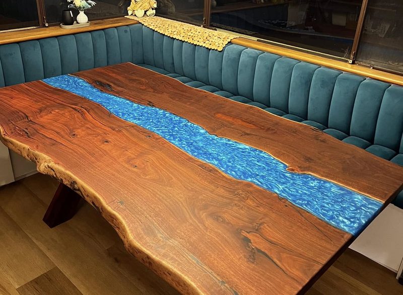 A live-edge dining table with a blue resin river